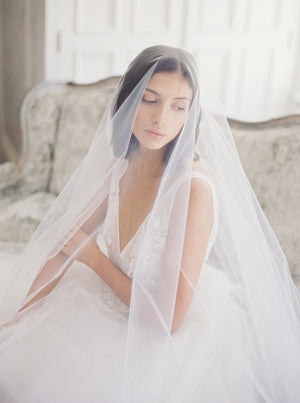 Close-up bridal portrait at Graydon Hall Manor, of a seated bride, wearing the sheer Amelie wedding veil over her face.