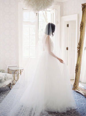 Bride standing by a window at Graydon Hall Manor, wearing the AMELIE Bridal Veil with Blusher and a full tulle ballgown. 