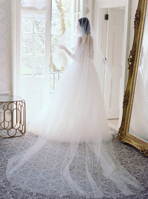 Full length shot of the bride at Graydon Hall Manor, showcasing the long, wide train of the sheer Amelie bridal veil with blusher, complementing her tulle ballgown.