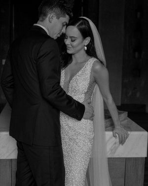 An intimate black and white photo of the bride and groom sharing a quite moment. The bride is wearing a beaded gown and the Annabelle wedding veil with side-parted hair down.