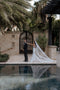 The Annabelle wedding veil catches the wind, billowing dramatically behind the bride as she reaches out to the groom in a tropical courtyard setting.