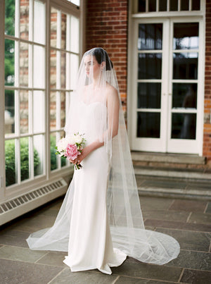 Bride wearing the ARIA sheer wedding veil with blusher in cathedral length.