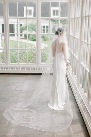 Bride wearing the ARIA sheer wedding veil with blusher in cathedral length.