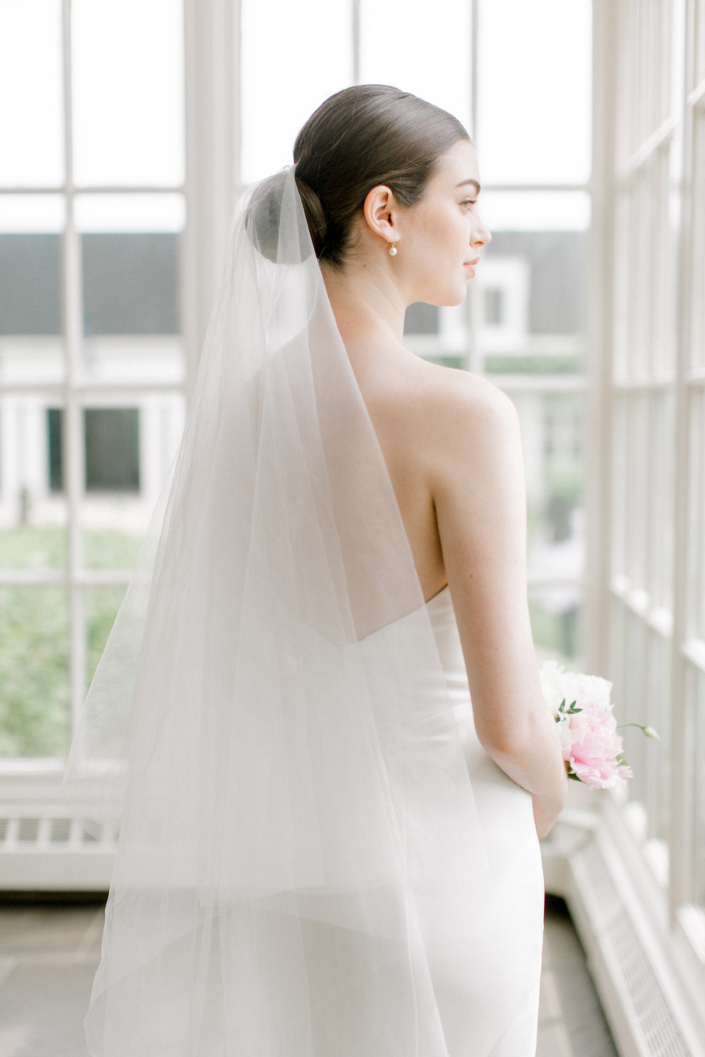 Bride wearing the ARIA sheer wedding veil with blusher; the blusher is shown worn at the back.