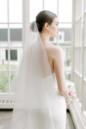 Bride wearing the ARIA sheer wedding veil with blusher; the blusher is shown worn at the back.