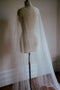 Full-length studio shot of the ARIELLE pearl cape on a mannequin, showcasing the length of the chapel-style train with pearls scattered all the way to the floor.