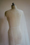 Back close-up of the ARIELLE bridal cape, focusing on the sheer tulle and the neckline, draped over a plain mannequin form.
