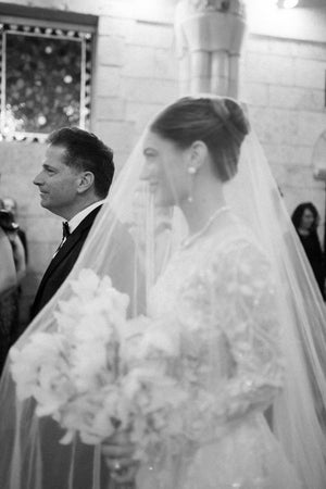 Close-up profile of the Cassandra long blusher wedding veil covering the bride's face. The veil is styled with a high updo.