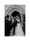 Post-ceremony embrace under a stone archway. The Cassandra veil's Italian tulle train pools on the ground as the bride is hugged by the father.