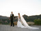 Bride and groom walking hand-in-hand with a mountain view; the bride is wearing the Dream Butterfly Veil with a crepe mermaid wedding dress.