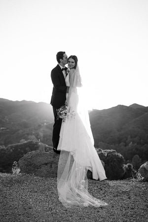Side profile view of the bride showcasing the Dream Butterfly Veil's sheer tulle and the delicate, butterflies appliques draped over her shoulder and mermaid gown.