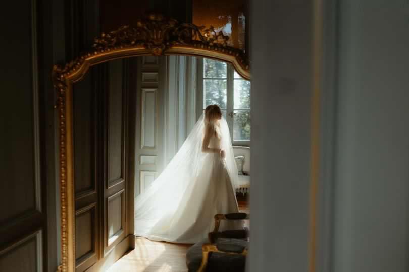 Silk wedding veil on beautiful bride in wedding gown walking through French chateau.