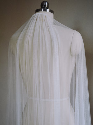 The Isabelle silk wedding veil shown on a dress mannequin, with the veil draped over the shoulders to showcase the softness of the tulle.