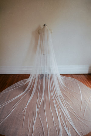 The Isabelle silk wedding veil shown at full height on a mannequin. The cathedral train is fully fanned on the floor.