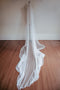 The Isabelle silk veil styled on a dress mannequin, with the train of the veil softly pooling on the ground to show the softness and fluidity of the silk tulle.