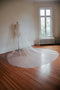 The Isabelle silk wedding veil shown on a mannequin from a distance, with the extra wide veil fanned out on the floor.