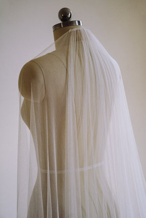 Up-close image of the Isabelle silk wedding veil on a dress dummy. The veil is draped over the shoulder, showcasing its softness and transparency. 
