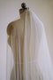 Up-close image of the Isabelle silk wedding veil on a dress dummy. The veil is draped over the shoulder, showcasing its softness and transparency. 