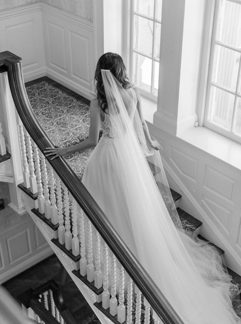 Bride wearing a cathedral silk wedding veil and lace wedding dress photographed on Graydon Hall staircase.