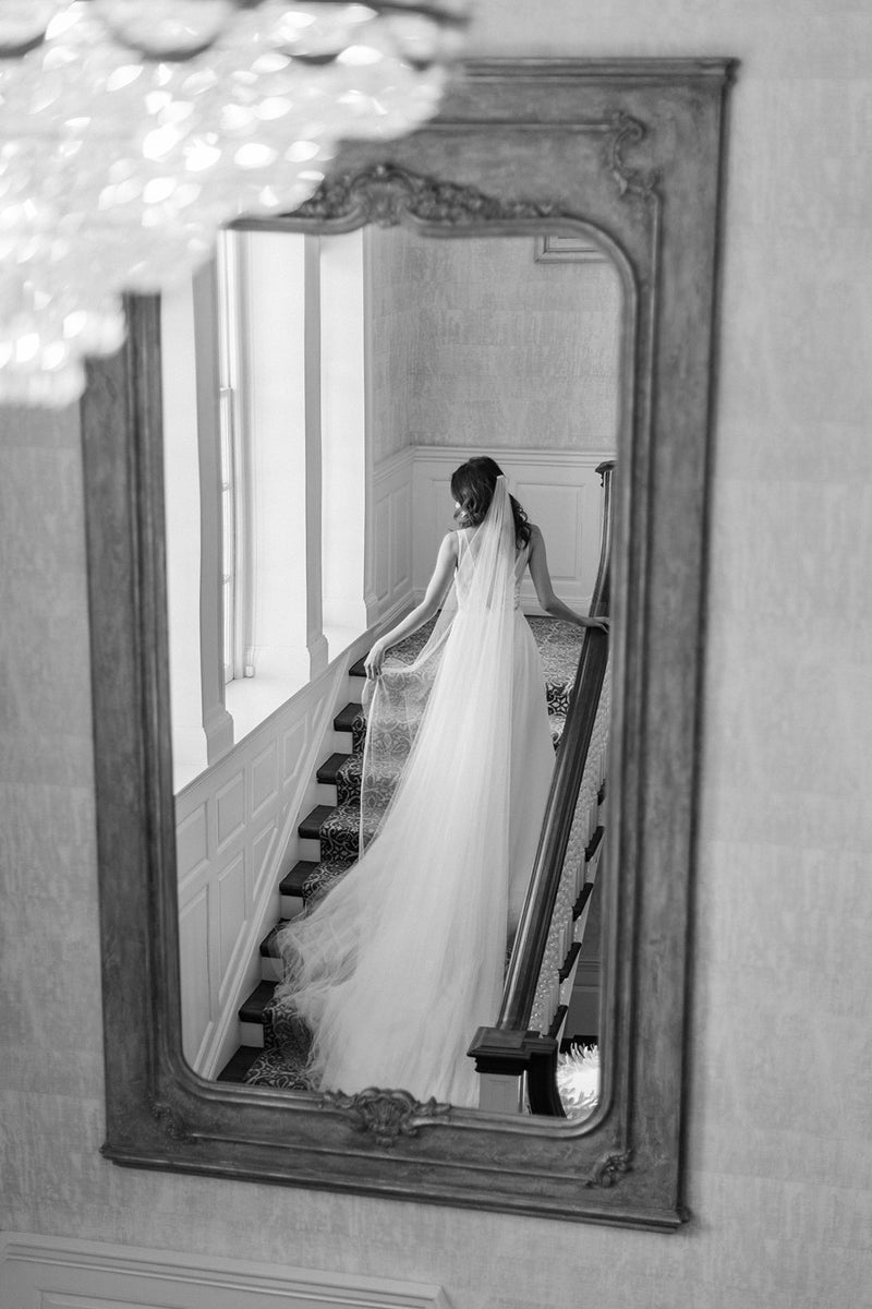 Bride wearing a cathedral silk wedding veil and lace wedding dress photographed on Graydon Hall staircase.