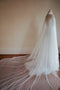 The Monique silk wedding veil with blusher shown from the side. The veil is draped over a dress mannequin, with the dramatic wide train fanned out on the floor.