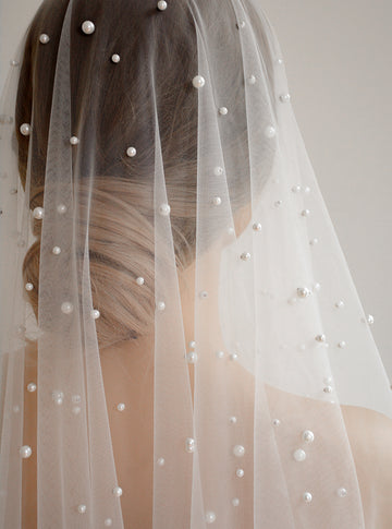 Close up of OPERA Pearl Veil on a bride, styled with a low updo, highlighting the varied sizes of scattered pearls.