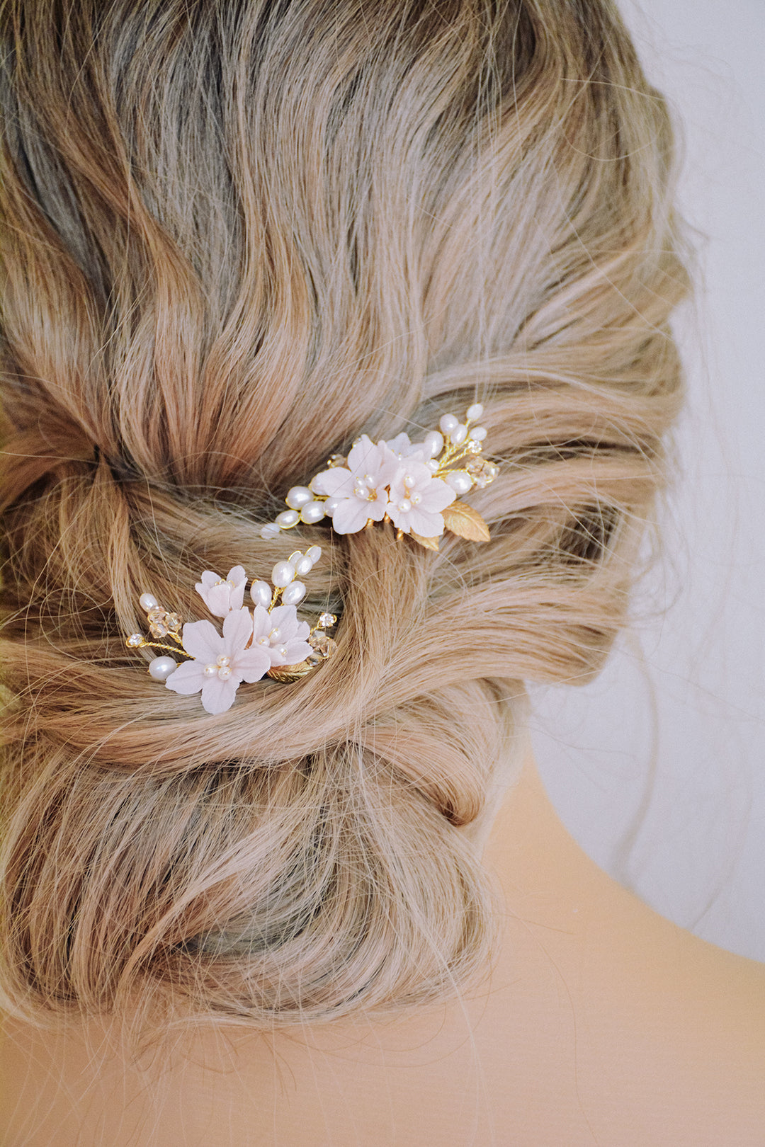 Blush bridal hair combs worn in a messy updo hairstyle.