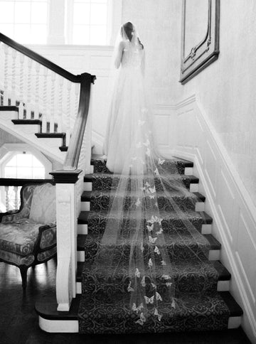A bride wearing the REVERIE wedding veil with butterflies while standing on the Graydon Hall staircase. 