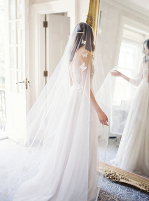A bride wearing the REVERIE wedding veil with butterflies and lace wedding dress; she is standing in front of the mirror in the Graydon Hall bridal suite. 
