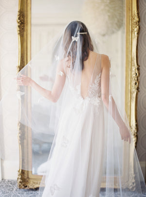 A bride wearing the REVERIE wedding veil with butterflies and lace wedding dress; she is standing in front of the mirror in the Graydon Hall bridal suite. 
