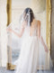 A bride wearing the REVERIE wedding veil with butterflies and lace wedding dress; she is standing in front of the mirror in the Graydon Hall bridal suite. 
