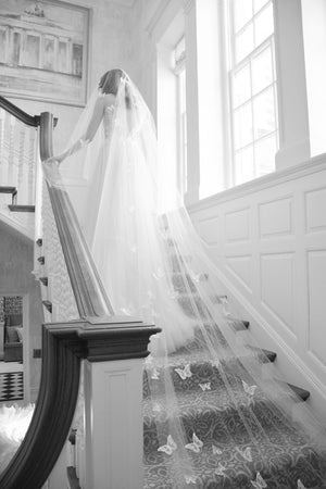 A bride wearing the REVERIE wedding veil with butterflies while standing on the Graydon Hall staircase. 