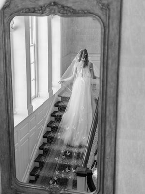 A bride wearing the REVERIE wedding veil with butterflies while standing on the Graydon Hall staircase. 