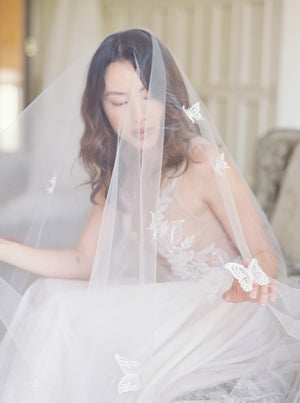 A bride wearing the REVERIE wedding veil with butterflies.