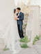 Bride standing on stairs with the Talitha single-tier veil spread out on the steps behind her.
