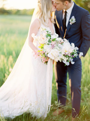 Fine art wedding photograph of a bride wearing the Talitha veil outside in golden hour lighting. 