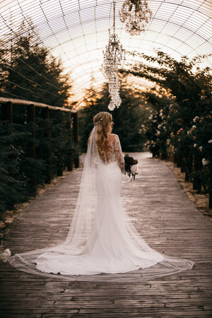 The Talitha wedding veil on a bride wearing a mermaid wedding dress. The veil is in cathedral length and is styled with soft waves.