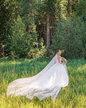 Bride standing outside with the Talitha long English net veil fanned out beautifully on the ground.