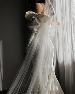 The Talitha veil show on a bride wearing a fitted bow detail dress. The veil is soft and sheer and drapes beautifully. 