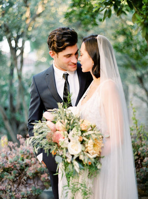 Profile shot of a bride wearing the Talitha veil. The photo shows the sleek, ungathered design in the hair. The veil is styled with a bob hairstyle, with the veil worn on the crown of the head. 