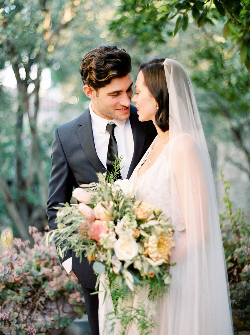Profile shot of a bride wearing the Talitha veil. The photo shows the sleek, ungathered design in the hair. The veil is styled with a bob hairstyle, with the veil worn on the crown of the head. 