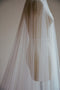 A close-up detail shot of a sheer Juliet cap wedding veil on a mannequin, highlighting the drape of the delicate French silk tulle as it falls gracefully past the waist
