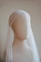 A front view of a bridal mannequin wearing the Lilybeth silk Juliet cap wedding veil with the blusher flipped back. The delicate French silk tulle smoothly hugs the crown of the head and cascades softly down the sides, covering the shoulders.