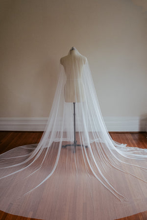 The Lilybeth Juliet cap veil shown on a mannequin. The veil is fully fanned out on the ground, creating a wide, dramatic train.
