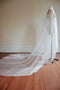 A side view of a mannequin wearing the Lilybeth Juliet cap wedding veil in cathedral length. The flowing French silk tulle falls elegantly down the back and fans out into an extra-wide train on the floor.