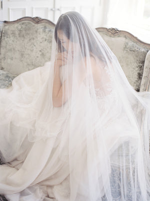 Close-up of the bride seated in the bridal suite at Graydon Hall Manor. The sheer Angelique Silk Drop Veil drapes gently over her face and shoulders, highlighting the softness of the French silk tulle.