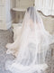 A full-length bridal portrait in Graydon Hall Manor. The bride is seated on an antique sofa, covered entirely by the soft and luxurious Angelique French Silk Drop Veil.