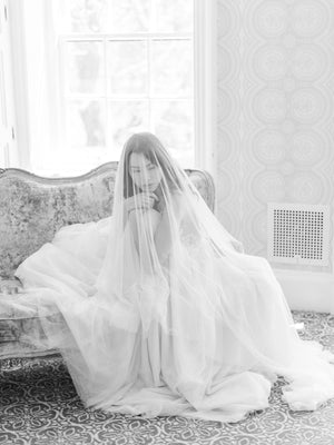 Black and white seated portrait in Graydon Hall Manor. The blusher of the Angelique French Silk Drop Veil is worn over the bride's face for a romantic feel.