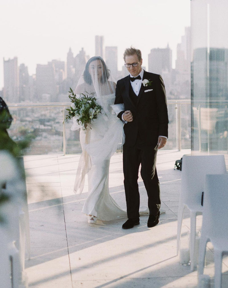 Real bride walking down the aisle on a rooftop in New York, wearing the blusher of the Angelique silk drop veil over her face.