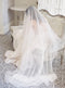 Full-length shot of a bride sitting on an antique sofa at Graydon Hall Manor. The Angelique French silk drop veil is draped over her and softly pools on the floor.